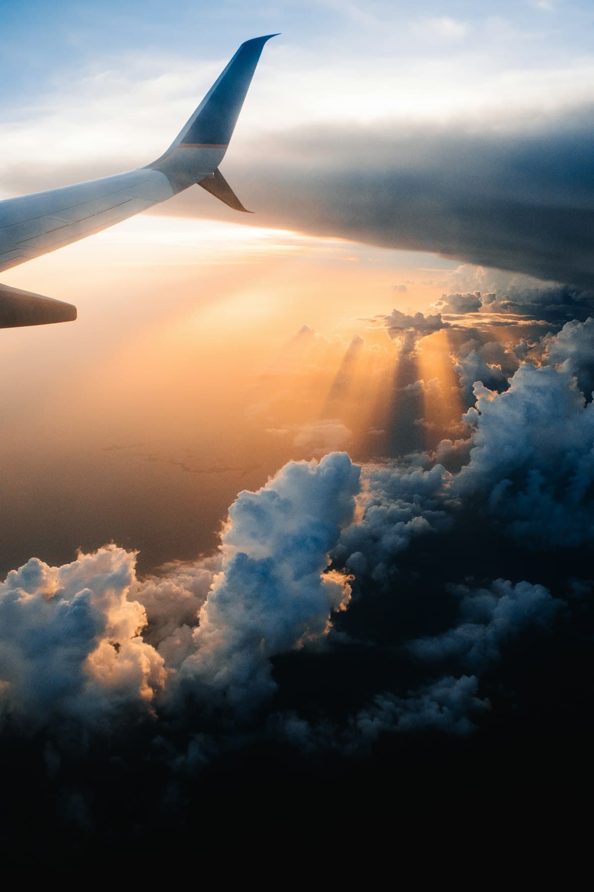 Flugzeugtragfläche über Wolken bei Sonnenuntergang — Symbol für den Abflug